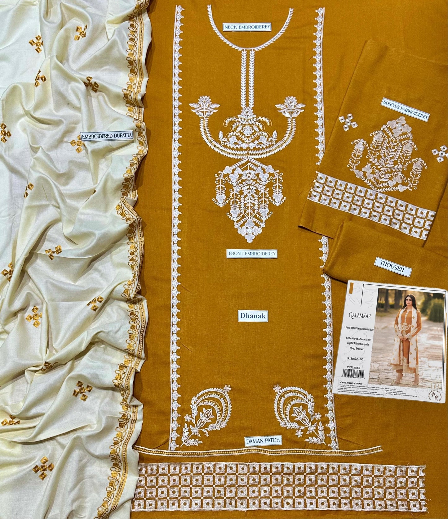 Mustard yellow fabric with white embroidery and a white saree with gold patterns.
