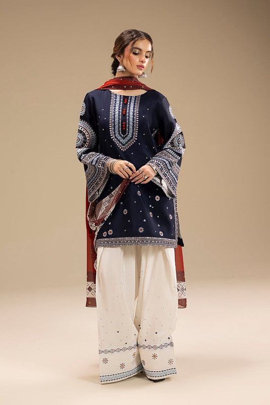 Woman wearing a navy blue embroidered top and white pants with a red dupatta on a beige background