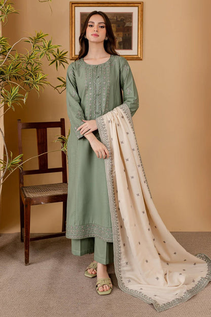 Woman in a green traditional outfit with a beige dupatta against a beige wall.