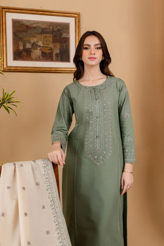 Woman wearing a green embroidered kurta with beige dupatta against a beige wall.