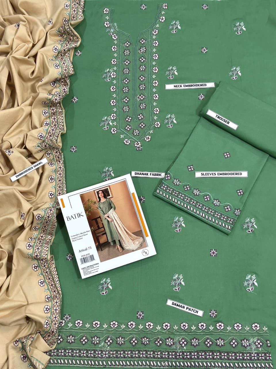 Green fabric with embroidery patterns and a magazine on a beige fabric background