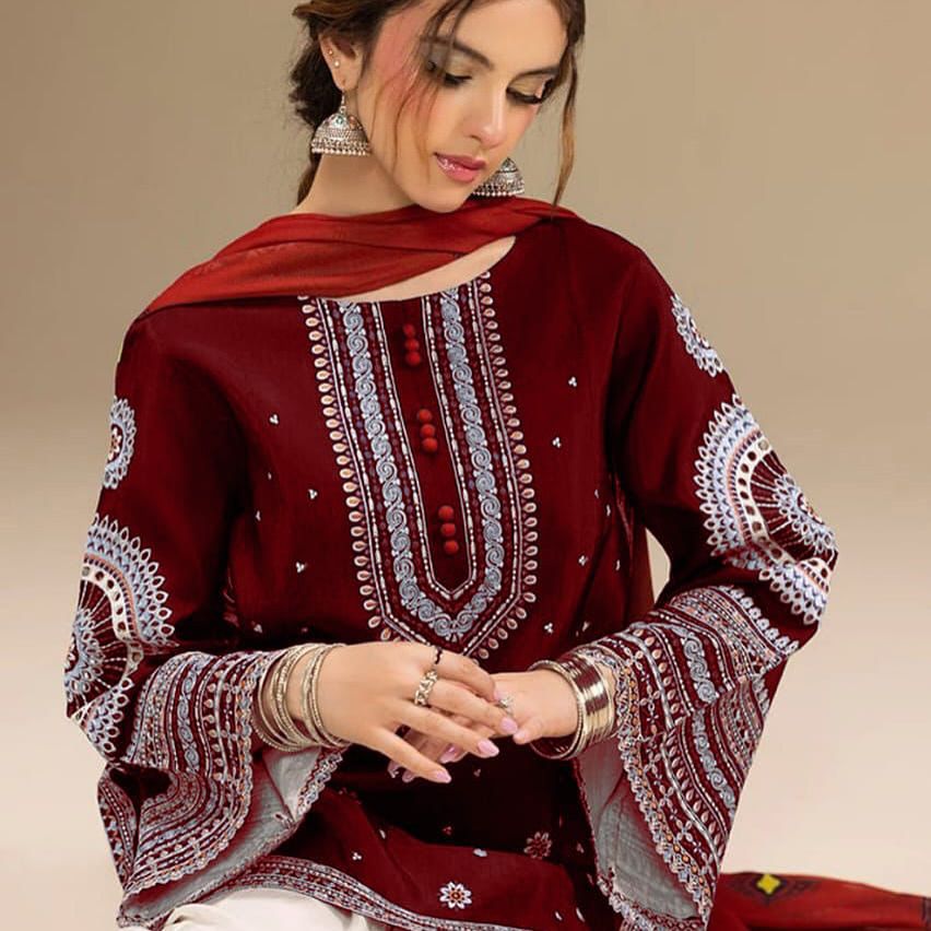 Woman wearing a maroon embroidered traditional outfit with a beige background