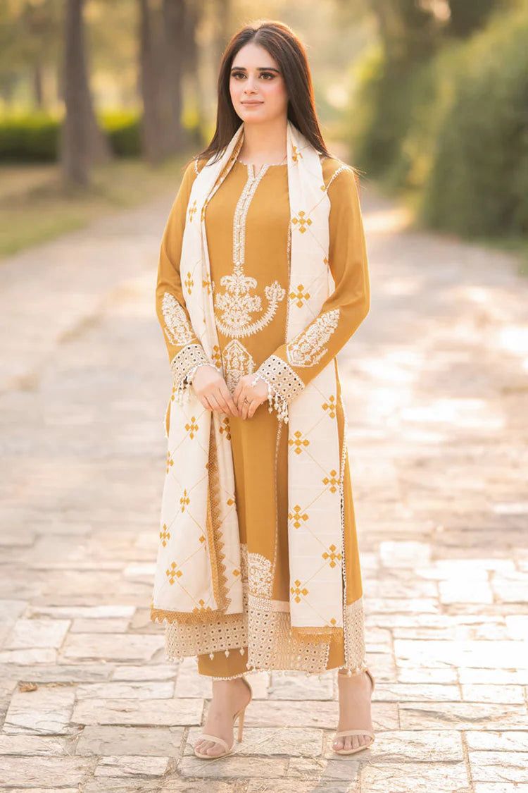 A woman wearing a mustard yellow and white embroidered traditional outfit standing outdoors on a paved path.